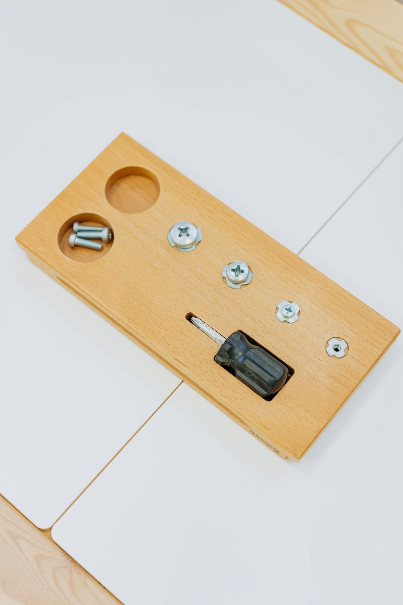 Flat lay of a wooden board with a screwdriver and screws for DIY projects.